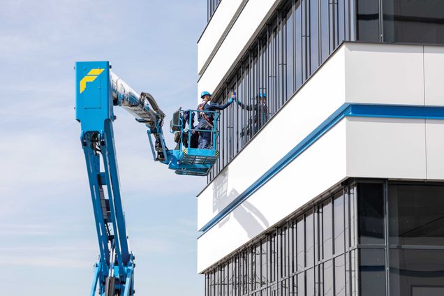 Slide Arbeiter auf Arbeitsbühne tragen eine PSAgA beim Reinigen der Fenster der Felbermayr Zentrale in Wels. 
